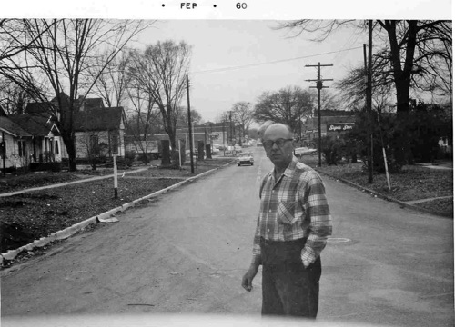 Clayton O. Nordan standing in the curve of Main Street looking south, near the location of Eclipse Coffee House today. The photo was shot to chronicle the cutting of the large trees on Main Street. Several tall stumps can be see at left. The first house on the left was the home of W.M. Wyatt. The house next door was the "Crowe" house that became the first location of Hoffman/Rockco Funeral Home.